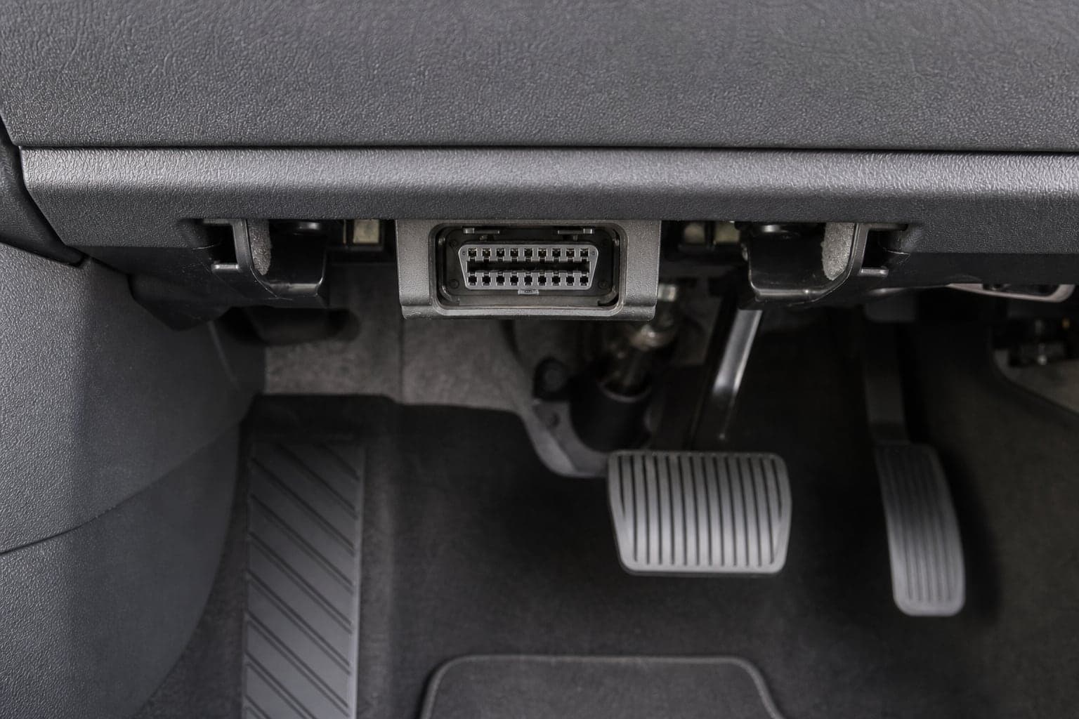 Illustrative AXLEWARD campaign render of an exposed 16-pin diagnostic socket beneath a vehicle dashboard
